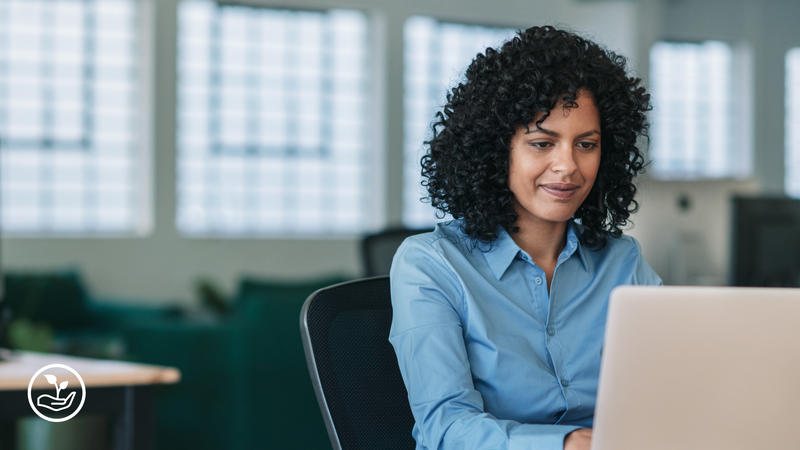 A woman sitting at a desk looking at a laptop