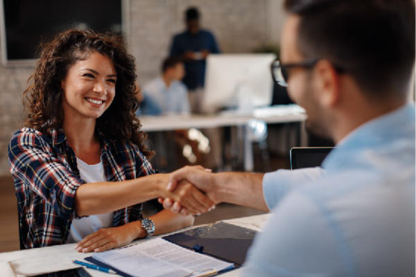 Young man and woman smile and shake hands in an office setting